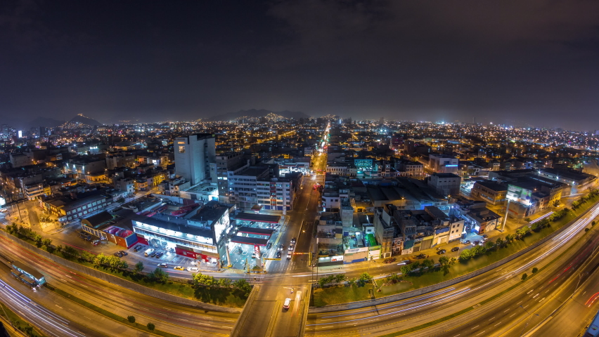 Panoramic skyline of Lima city from above with many buildings aerial night timelapse. Poor houses with hills on a background. Traffic on streets and Via Expresa highway. Lima, Peru