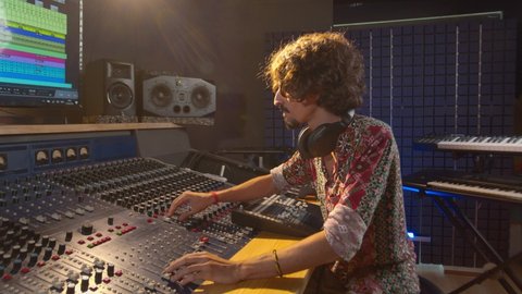 Music studio. Creative energy. Producer. Latin man working in the recording studio. Attractive brunette male person in a beautiful shirt produces songs. 