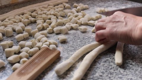 Chef cutting rolls of potato dough for the preparation of homemade gnocchi