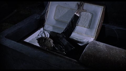 CIRCA 1972 - In this classic horror film, a vampire lifts the lid on his coffin in a graveyard.