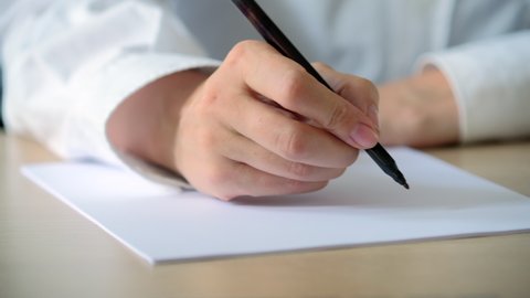Woman writing letter on a piece of white paper. Closeup of female hands write notes. Writing essay or love letters