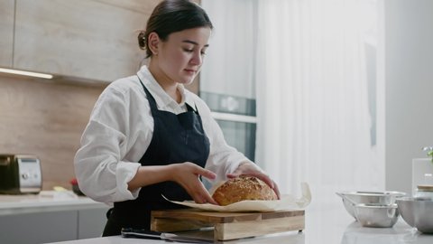 Young Baker Girl Checks Bread for Readiness.