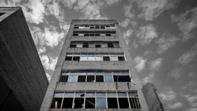 Low angle time lapse glitching video in the window frames of an empty disused concrete building with clouds moving in the sky, El Poblenou, Barcelona, Spain