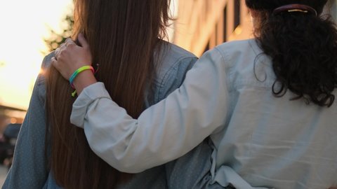 Two lesbian woman lgbt couple girlfriends hugging, holding hands with rainbow bracelets outdoors. Gay lesbians bisexual transgender. Concept LGBT happiness freedom love homosexual couple 4 K slowmo