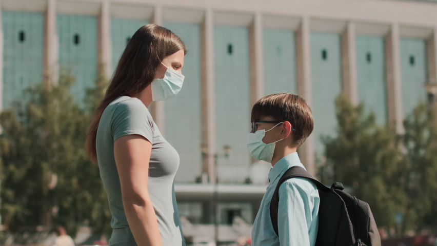  Back to school, Happy schoolboy, Learn lessons. A woman in a mask takes her child to school and hugs him. School season during a pandemic Royalty-Free Stock Footage #1058396098