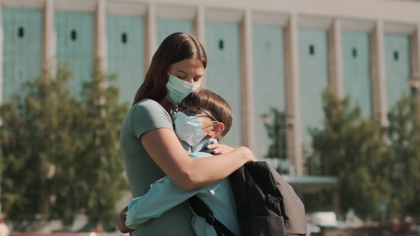  Back to school, Happy schoolboy, Learn lessons. A woman in a mask takes her child to school and hugs him. School season during a pandemic Royalty-Free Stock Footage #1058396098