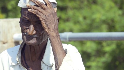 LATUR , MAHARASHTRA / India - 08 29 2020: An old poor farmer from Indian rural village area of Latur is seen scratching his head.