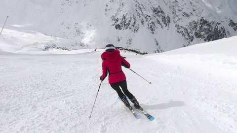 Girl skiing elegangt short turns on a steep ski-pist.