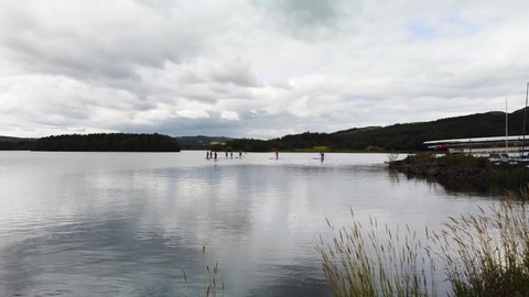 Paddleboard training on a Scottish Loch. Grey cloudy sky above and calm water making it easier