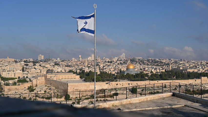 View of Temple Mount with Dome of the Rock and Al Aqsa Mosque, archaeological park of the Southern Wall and Huldah Gates, and skyline of new Jerusalem over the Old City; with Israeli flag in the front Royalty-Free Stock Footage #1058405047