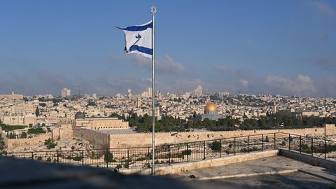 View of Temple Mount with Dome of the Rock and Al Aqsa Mosque, archaeological park of the Southern Wall and Huldah Gates, and skyline of new Jerusalem over the Old City; with Israeli flag in the front