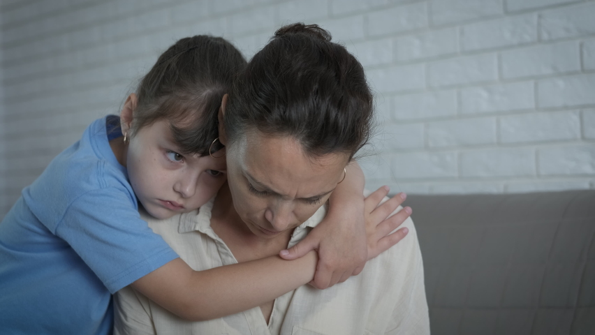 Sad family relationship. A sad child hugs her crying mother in the room. A concept of problem and conflict in the family. | Shutterstock HD Video #1058409616