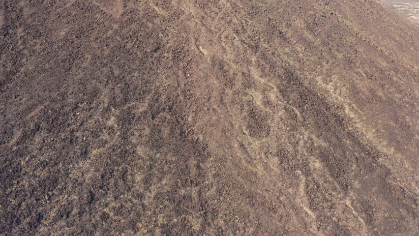 Aerial fly around view of the abstract texture of the ground around the volcanic Amboy Crater in the Mojave Desert.