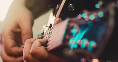 Musician playing on electric guitar. Close-up view fingers on neck, colour bokeh. Rock, Blues, Jazz, Pop music style play on concerts, recording in studio. Artist hobby, Create own melodies and songs.
