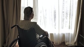 Disabled woman sit on wheelchair and looks through the window - Powered by Shutterstock - Get 15% off with code: PIKWIZARD15