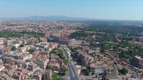 Aerial view of Colosseum in Rome, famous ancient amphitheater and ruins of ancient city center in foreground - landscape panorama of Italy from above, Europe