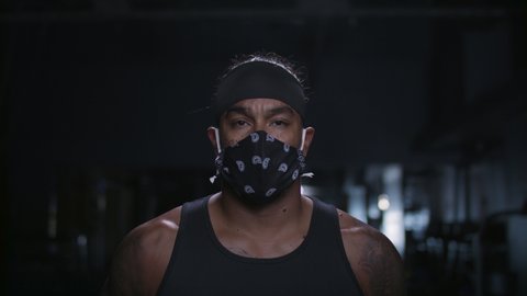 Mask at the gym! Strong and powerful portrait of a diverse athlete. Focused on achieving his goals. Pandemic and social distancing. Shot in 4k.  