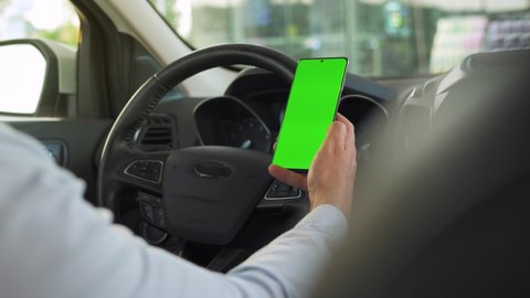 Driver using a smartphone inside the car. Chromakey smartphone with green screen. Auto navigation. Internet addiction