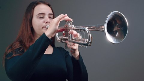 Young woman playing piccolo trumpet. Trumpeter playing music jazz instrument