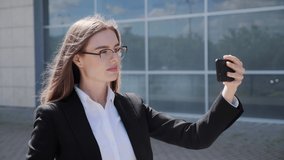Pretty girl in business clothes talking on the phone using a mobile phone for video link. Business lady waving hand holding a smartphone.Internet media communication