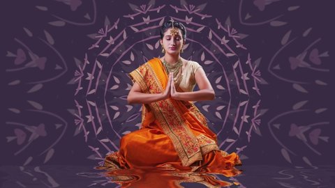 Indian woman in orange saree meditating over beautiful animated mandala background