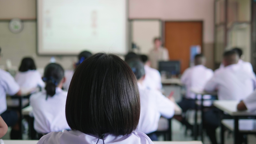 Slow motion of Asian high school students in white uniform actively study science by raising their hands to answer questions on projector screen that teachers ask them  in science classroom. Royalty-Free Stock Footage #1058423449