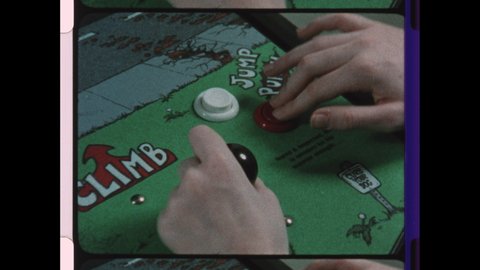 1980 United States. Two Boy's play Rampage the Vintage Arcade Game. Close-Up of teenage Hands on Joy Stick.  4K Overscan of Archival 16mm Film with Edge Lines and Sprocket Holes