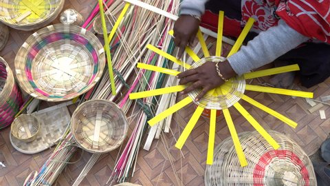Kolkata, West Bengal, India - 31st December 2018 : Working Indian female artist's hands, weaving wicker basket handicrafts. Indian handicrafts are famous for colourful and detailed art. 4K footage.