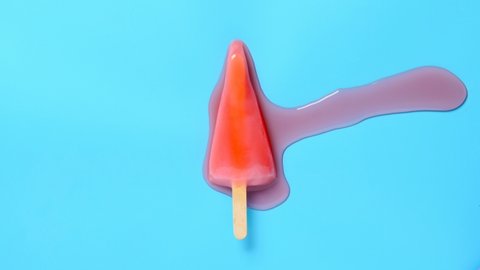 top view watermelon slice shape and flavor popsicle melting on a blue background timelapse 8K
