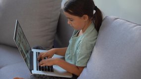 Cute child use laptop for education, online study. Girl has homework at home schooling.