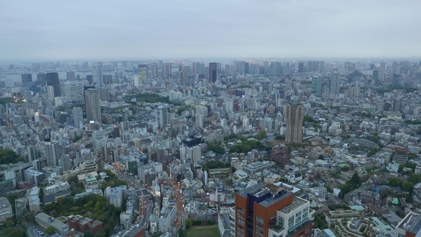Big Tokyo metropolis cityscape at evening twilight. Time lapse panoramic shot, lively car motion seen on small streets. Mixed residential development of Minato ward, aerial view