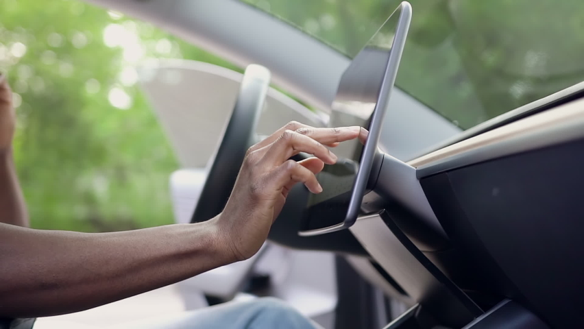 Side view of unrecognizable black-skinned man which typing needed coordinates on navigator touchscreen while speaking on smartphone inside his auto | Shutterstock HD Video #1058438653