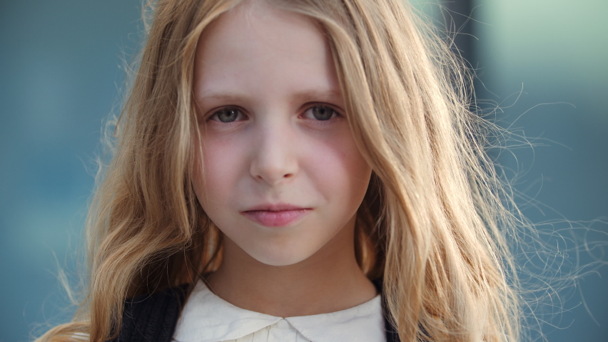 Portrait of upset sleepy little schoolgirl looking at camera with sadness and resentment in her eyes, lonely kid cute lady crying, wiping tear from her face with child hand, negative bad mood concept