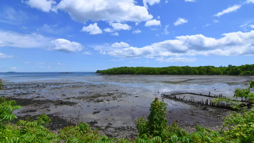 Wide angle time lapse daytime of Glen Cove in Rockport, Maine at low tide in beautiful shallow bay with cumulus clouds drifting in sky