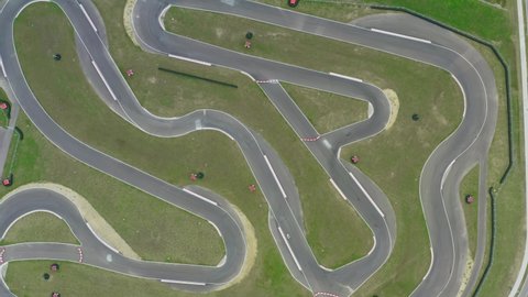 Aerial top down view drone flies over white racing car driving on winding race track. Cloudy summer day. Kart racing open wheel motorsport. Racing go-karts competition