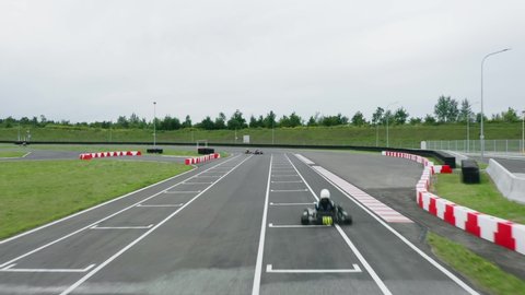 Aerial view drone flies low over racing cars driving on winding race track. Kart racing open-wheel motorsport. Racing go karts competition
