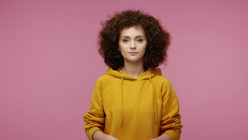 Insecure frightened young woman afro hairstyle in hoodie biting nails, feeling worried nervous about serious troubles, stress and anxiety disorder concept. indoor studio   isolated on pink background Royalty-Free Stock Footage #1058441836