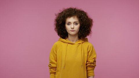 Confused displeased young woman afro hairstyle in hoodie feeling disgust repulsion to bad smell, pinching her nose holding breath to avoid stink, fart gases. indoor studio  isolated on pink background