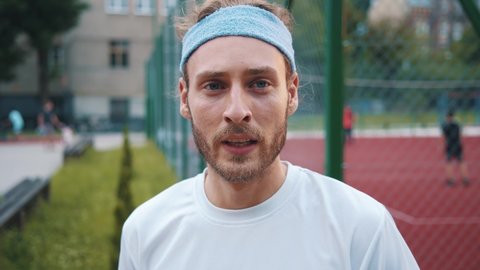 Attractive nice-looking young millennial athlete wearing headband smiling cheerful enjoying cardio workout outdoors. Runner portrait. Sports concept.