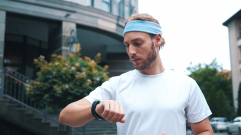 Attractive caucasian runner in sportswear using smartphone futuristic app interacting virtual user interface fitness characteristics outdoors. Technology and sports.