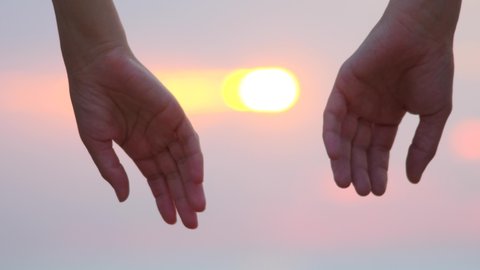 Close-up of hands joining together with sunlight flare in the background. Beautiful romantic moment between two lovers. Feelings, emotional romantic cinematic scene. First love, falling in love
