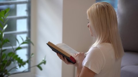 Young woman praying while holding Bible. Woman with Bible praying and reverencing God in her daily devotional at home. 4k