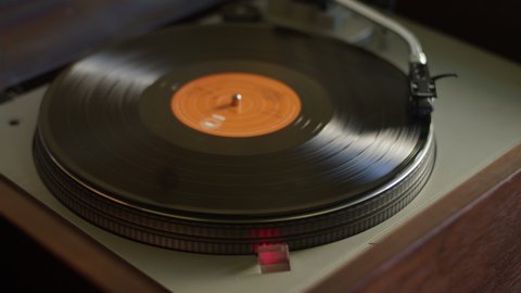 A vinyl record gets placed on a turntable and starts listening to music