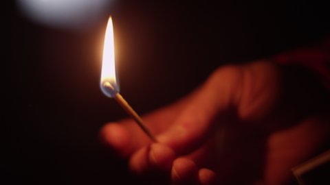 Close up of a matchstick being lit in a dark void
