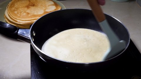 Cooks Pancake Blin on frying pan in home kitchen. Sweet Homemade Food for Breakfast