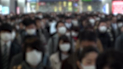 TOKYO, JAPAN - MARCH 2020 : Crowd of people walking at the station in morning rush hour. Commuters going to work. People wearing mask to protect from Coronavirus (COVID-19). Blurred slow motion shot.
