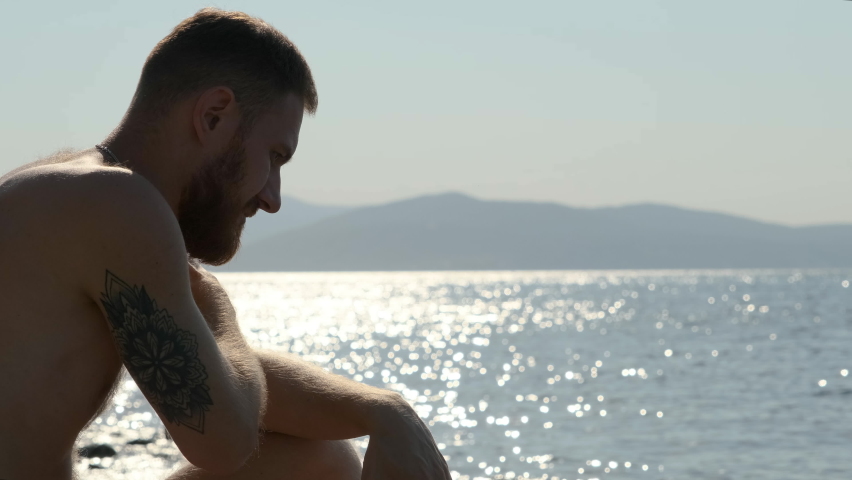 Guy sits on the beach or ocean and yawns. It is very boring for man at sea and he wants to go to the office.
