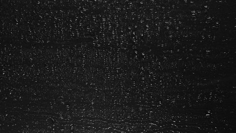 Rain Drops trickling down isolated on black background. Rain Drops Falling down on black glass background. Heavy Rainfall. Rainy at night, Raining at night. Droplets of water running down in 4K. 