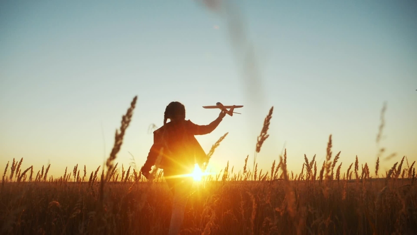 Girl kid run in the park across the field play with an toy airplane in his hand a silhouette at sunset wants to astronaut pilot. fun fantasy dream kid concept. child run fun wheat play with toy