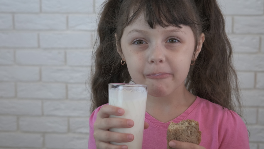 Tasty baguette with milk. A hungry child eat a piece of bread with a glass of milk for breakfast. | Shutterstock HD Video #1058463124